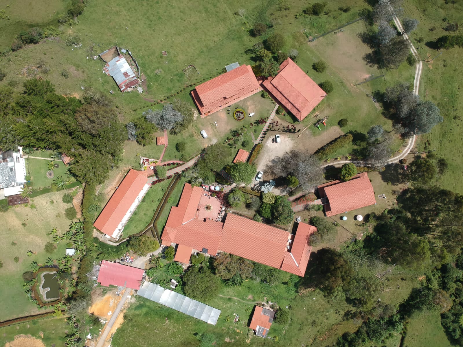 Vista aérea del conjunto de edificios de techo de teja, patios y jardines rodeados de colinas verdes