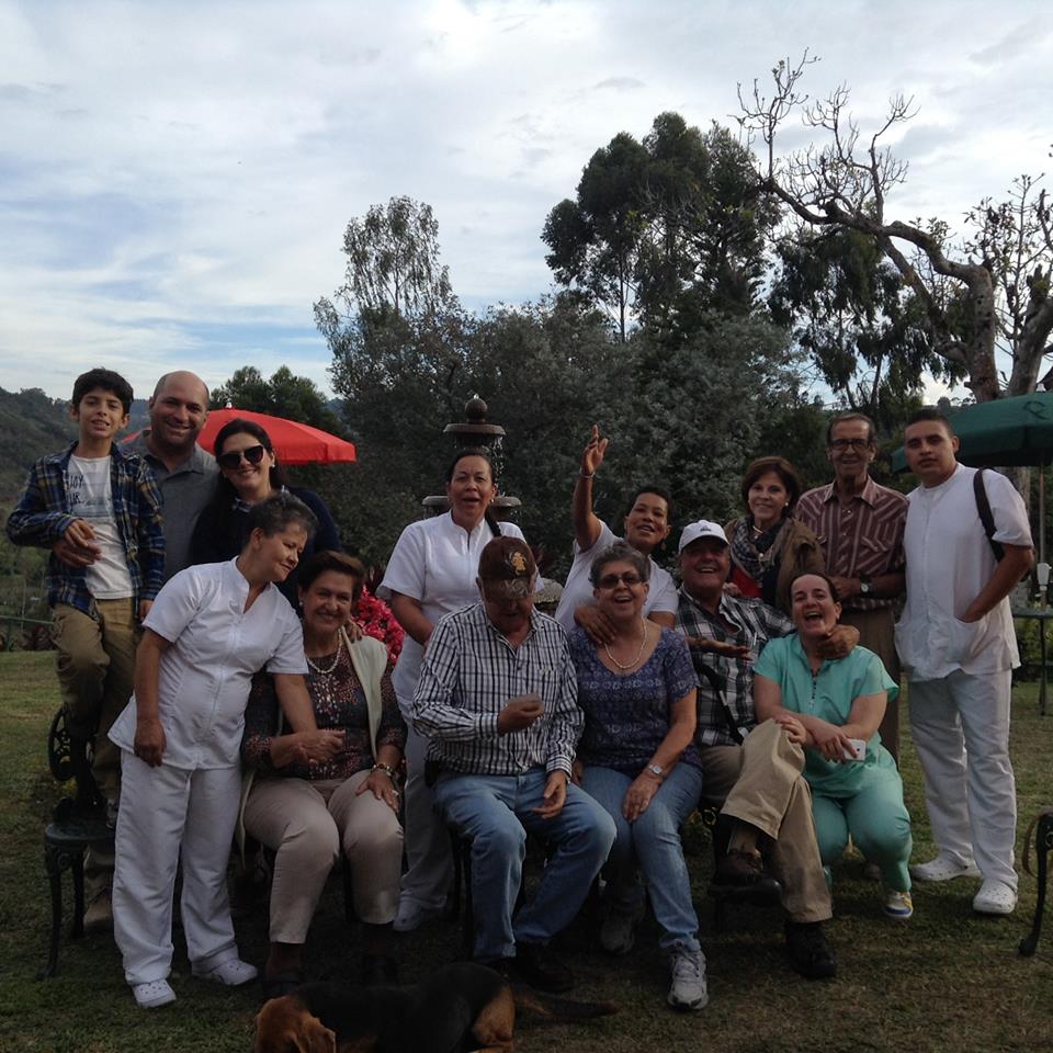Grupo de personas posando sonrientes en el jardín del hogar, con un perro en primer plano